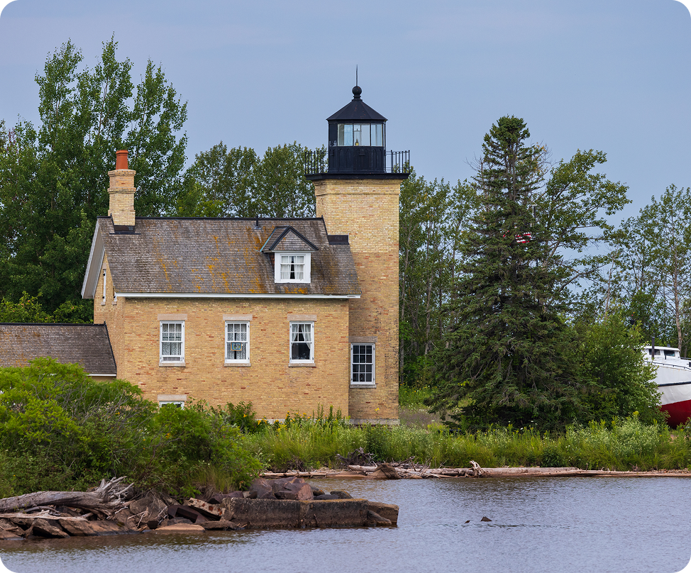 Historic lighthouse by the lakeside with trees.